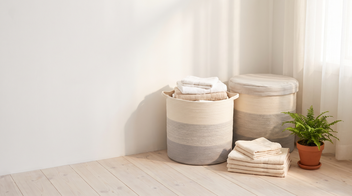 Woven cotton rope laundry baskets with folded linens in a bright Nordic home